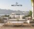 Luxury Mod Patio outdoor furniture set with a modern sofa, woven lounge chairs, coffee table, and plants overlooking a scenic lake and mountain landscape.